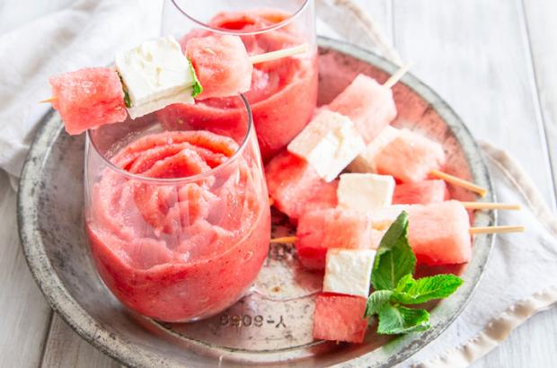 Watermelon Mint Frosé in a glass, served with watermelon and feta skewers