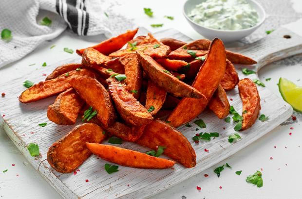 Spicy Sweet Potato Wedges on a Cutting Board with Jalapeno Sour Cream