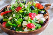 Colorful salad in a bowl with strawberries, blueberries, mozzarella ball slices and spring greens